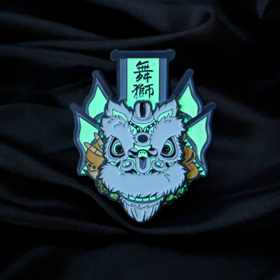 A stylized enamel pin or patch featuring a white and blue lion dance face with glowing green accents, black outlines, and a vertical sign with Chinese characters above it, displayed on a dark draped fabric background.